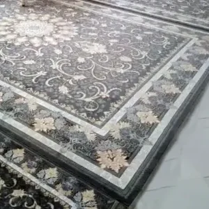 alt="کاور محافظ ریشه فرش رنگ طوسی که روی لبه فرش دستباف قرمز قرار گرفته و ریشه‌ها را پوشانده است."